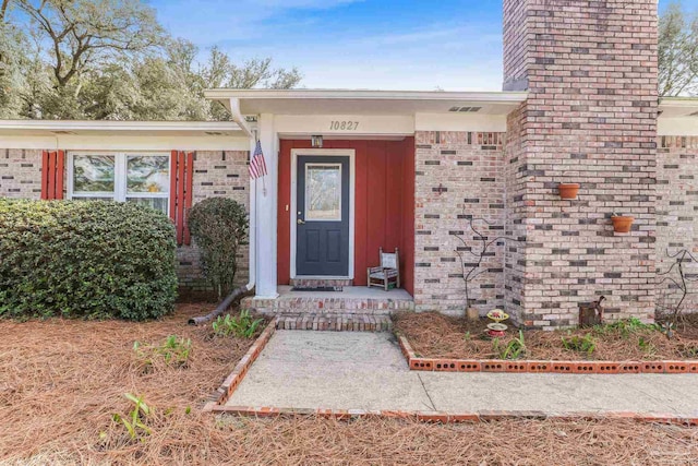 property entrance with a chimney and brick siding