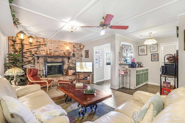 tiled living room featuring ceiling fan, a fireplace, and baseboards