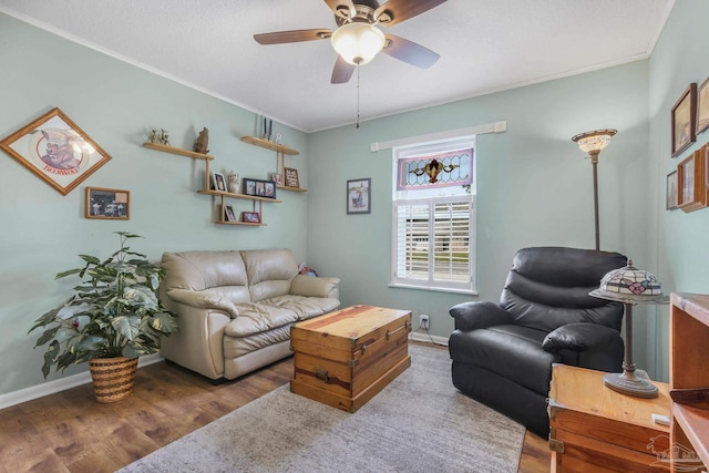 living area featuring ceiling fan, crown molding, baseboards, and wood finished floors