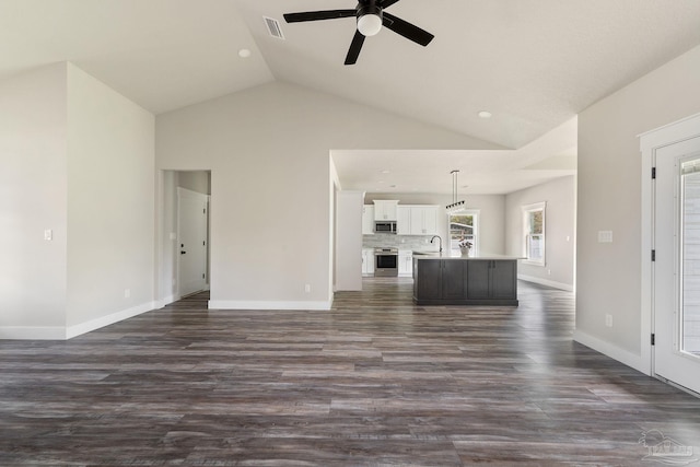 unfurnished living room with ceiling fan, a sink, baseboards, dark wood-type flooring, and visible vents
