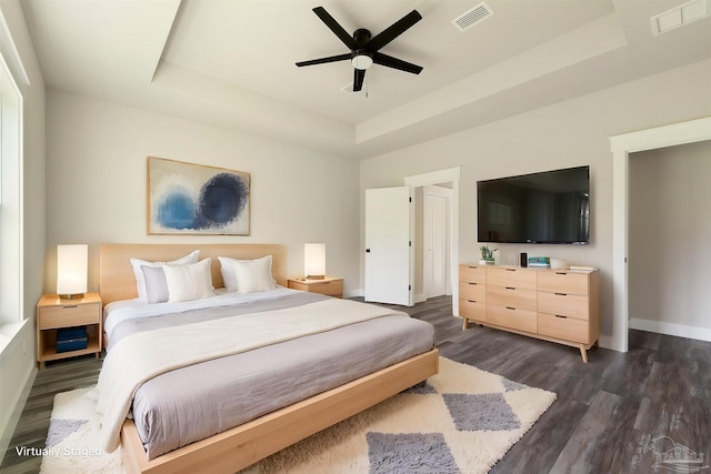 bedroom with baseboards, a tray ceiling, and visible vents