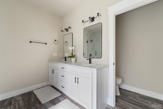full bath with baseboards, a sink, wood finished floors, and toilet