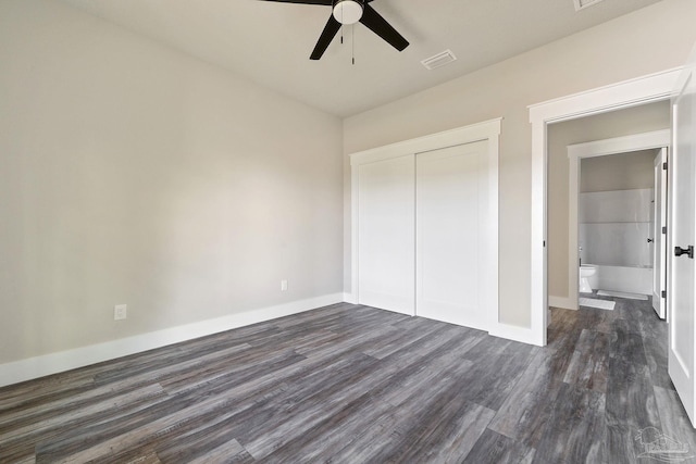 unfurnished bedroom featuring a closet, baseboards, visible vents, and dark wood-type flooring