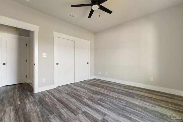 unfurnished bedroom with dark wood-style flooring, a ceiling fan, baseboards, visible vents, and a closet