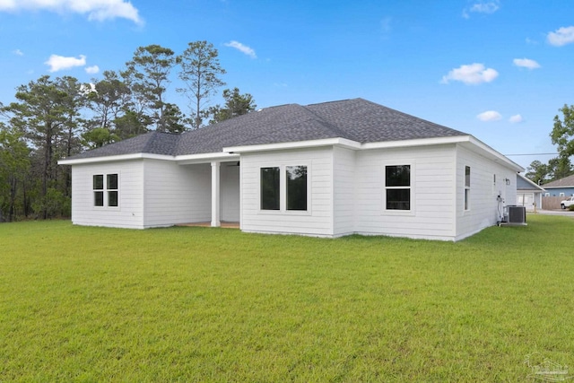 back of house with a lawn, cooling unit, and roof with shingles