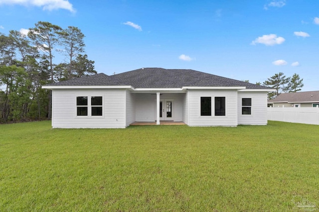 view of front facade featuring french doors, fence, roof with shingles, and a front lawn