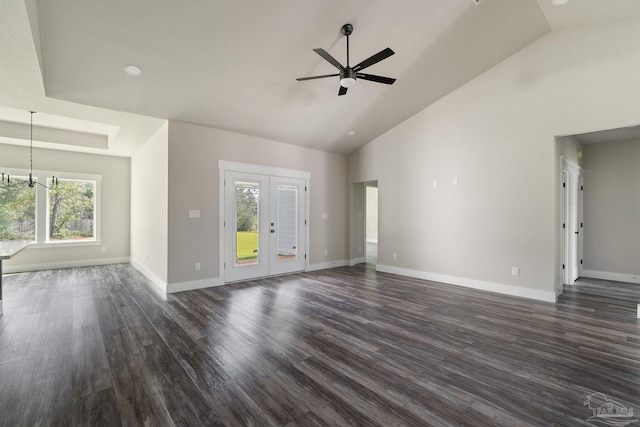 unfurnished living room featuring a healthy amount of sunlight, high vaulted ceiling, ceiling fan with notable chandelier, and dark wood-type flooring
