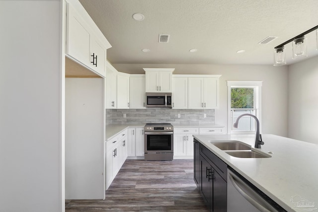 kitchen featuring visible vents, decorative backsplash, white cabinetry, a sink, and appliances with stainless steel finishes