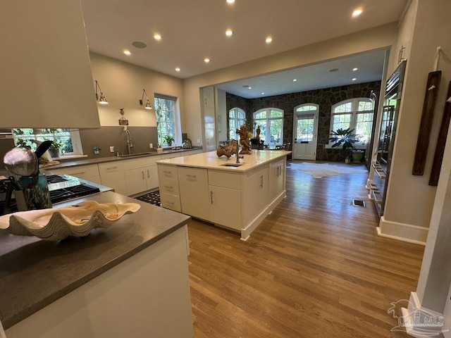 kitchen featuring sink, a kitchen island, white cabinets, and light hardwood / wood-style flooring