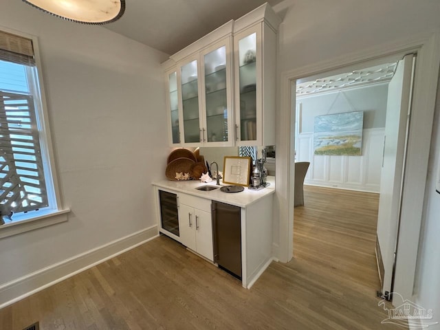 bar with wine cooler, white cabinetry, sink, and wood-type flooring