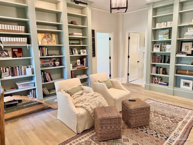 living area with hardwood / wood-style floors, a chandelier, and built in shelves