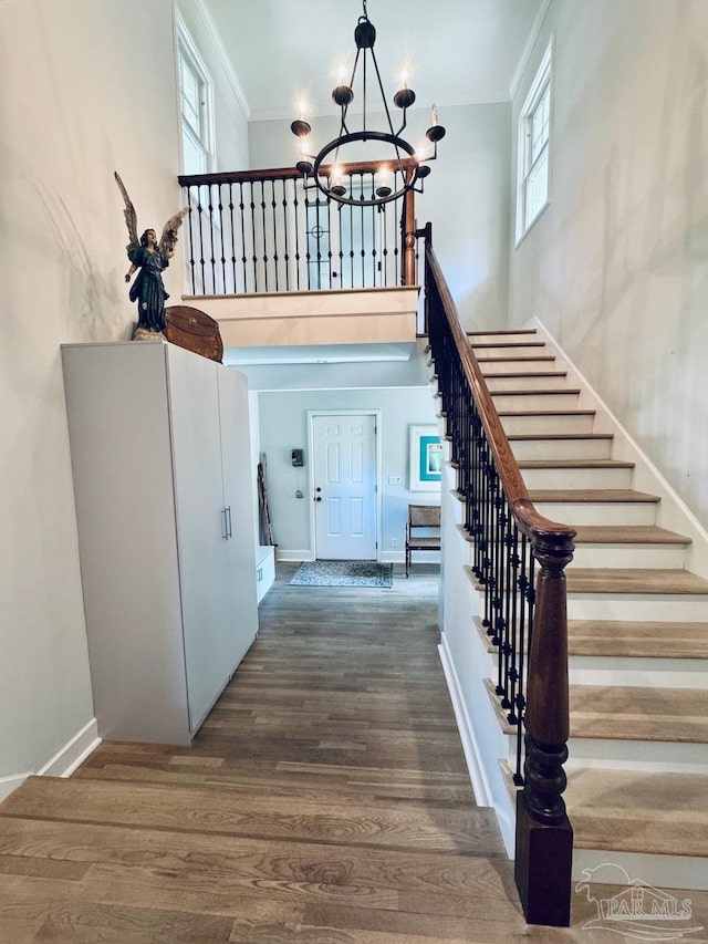 foyer with ornamental molding, dark wood-type flooring, and a chandelier