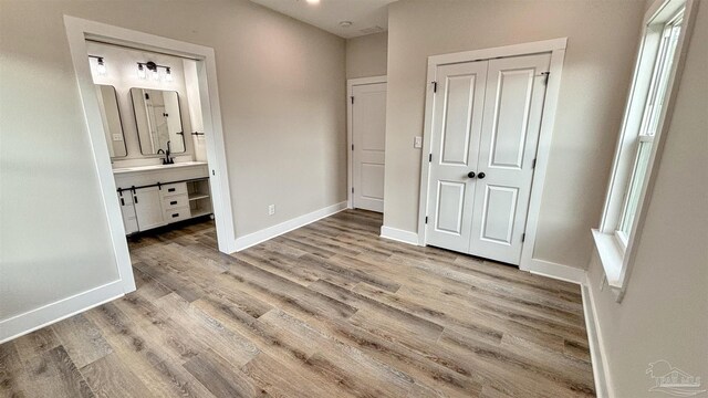 unfurnished bedroom with ceiling fan, a closet, connected bathroom, and light hardwood / wood-style flooring