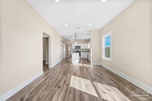 unfurnished living room with light hardwood / wood-style floors and a barn door