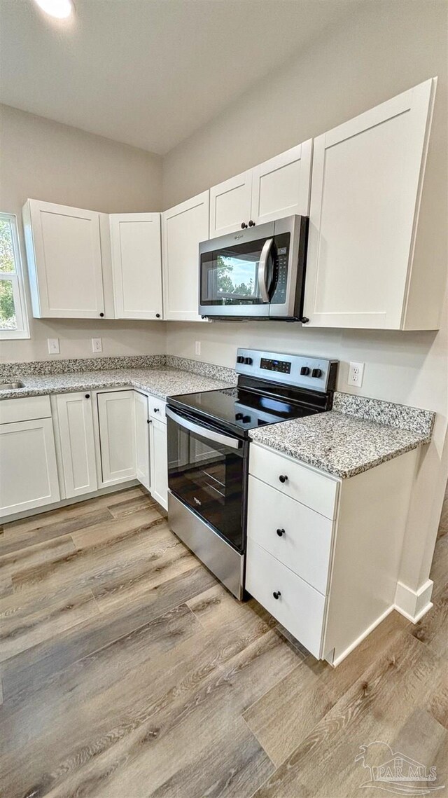 kitchen featuring white cabinets, a barn door, a kitchen island, and stainless steel appliances