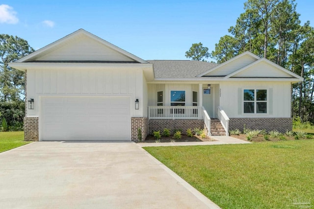 view of front of home with a front yard, covered porch, and a garage