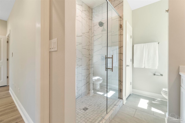 bathroom with a shower with door, vanity, toilet, and tile patterned floors