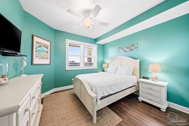 612 Lost Key Dr Unit 702-B, Pensacola, FL 32507 - bedroom with baseboards, dark wood-style flooring, a textured ceiling, and a ceiling fan