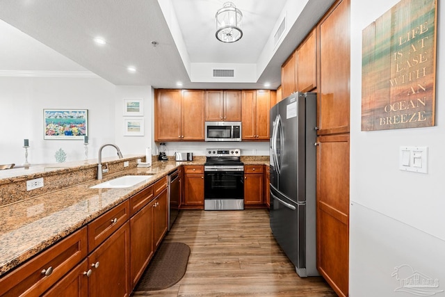 612 Lost Key Dr Unit 702-B, Pensacola, FL 32507 - kitchen featuring appliances with stainless steel finishes, a sink, light stone counters, brown cabinetry, and wood finished floors
