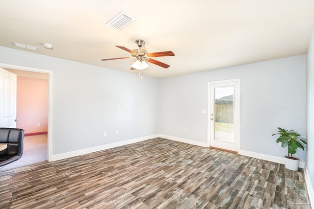 spare room featuring ceiling fan, visible vents, baseboards, and wood finished floors