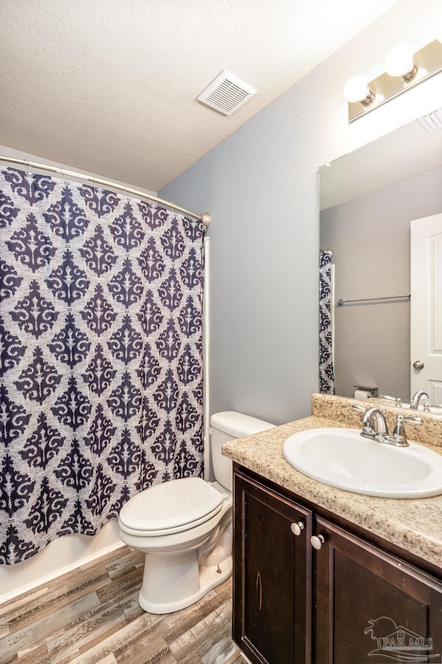 full bath featuring toilet, wood finished floors, visible vents, and a textured ceiling