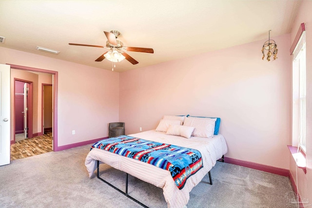 carpeted bedroom with visible vents, baseboards, and a ceiling fan