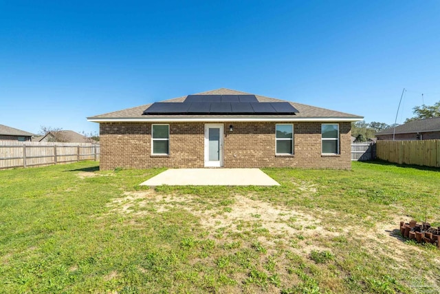 back of house featuring a patio, a yard, a fenced backyard, and brick siding
