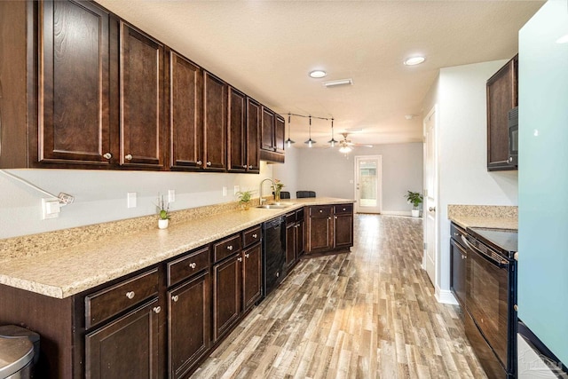 kitchen featuring visible vents, dark brown cabinetry, light wood-type flooring, black appliances, and a sink