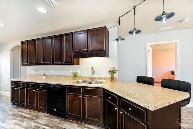 kitchen featuring a peninsula, arched walkways, a sink, black dishwasher, and light wood-style floors