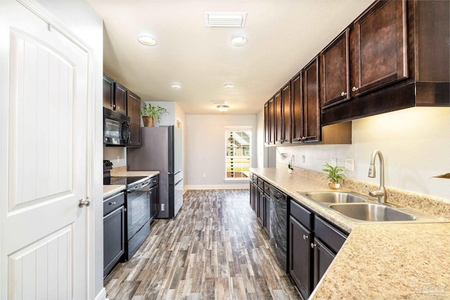 kitchen featuring visible vents, black appliances, a sink, light countertops, and dark brown cabinets