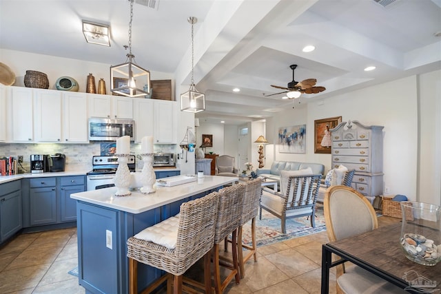 1430 Regency Rd Unit H103, Gulf Shores, AL 36542 - kitchen with stainless steel appliances, decorative backsplash, blue cabinets, light countertops, and a ceiling fan