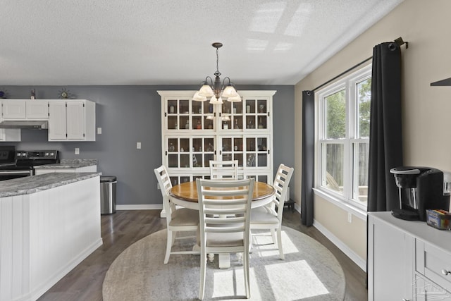dining room featuring a chandelier, a textured ceiling, baseboards, and dark wood-style floors