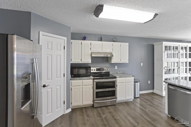 kitchen featuring a textured ceiling, white cabinetry, under cabinet range hood, appliances with stainless steel finishes, and dark wood-style floors