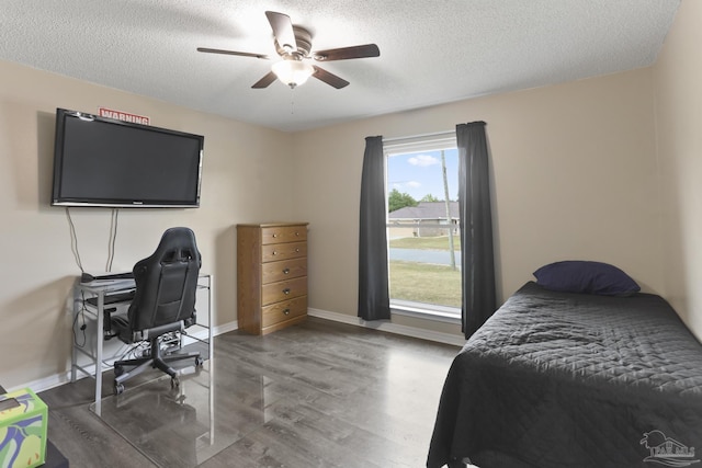 bedroom featuring a textured ceiling, baseboards, wood finished floors, and a ceiling fan