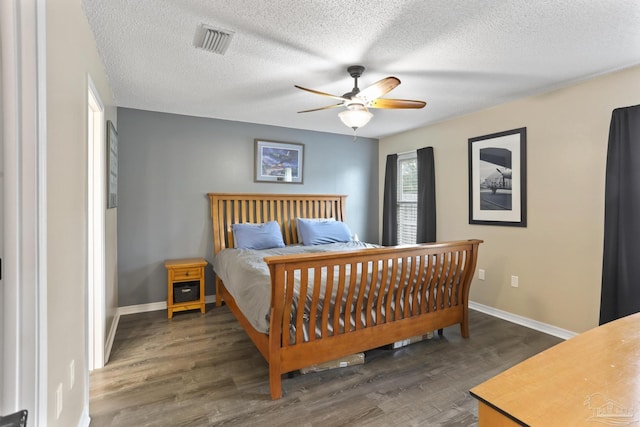 bedroom featuring a textured ceiling, baseboards, visible vents, and wood finished floors