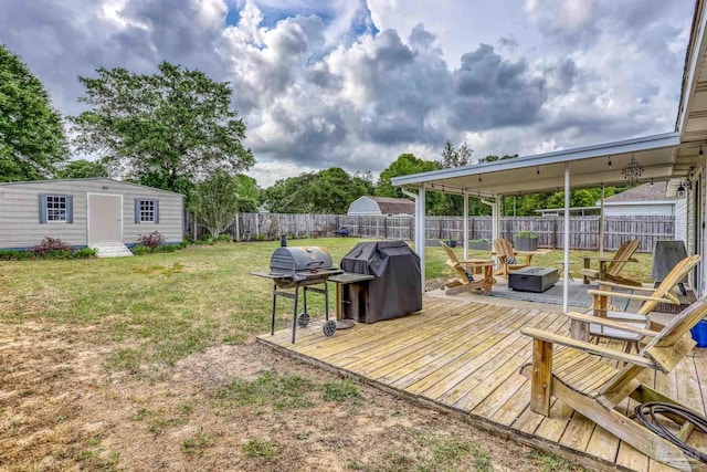 view of yard featuring a fire pit, an outbuilding, a wooden deck, and a fenced backyard