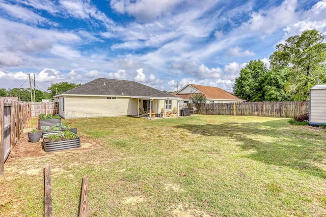 view of yard featuring a vegetable garden, a patio, and a fenced backyard