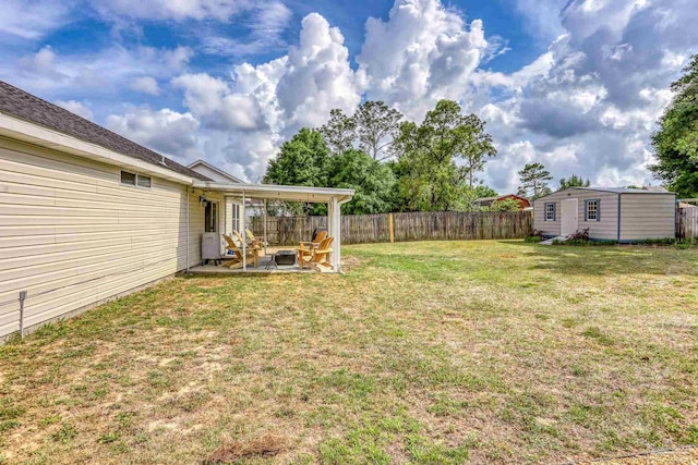 view of yard featuring a storage shed, a patio, an outdoor structure, and a fenced backyard