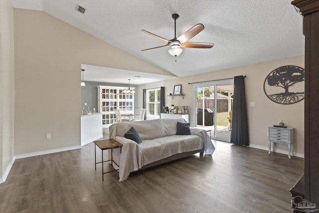 living room featuring dark wood-style flooring, lofted ceiling, ceiling fan with notable chandelier, and visible vents