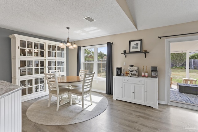 dining room featuring an inviting chandelier, a wealth of natural light, visible vents, and a textured ceiling