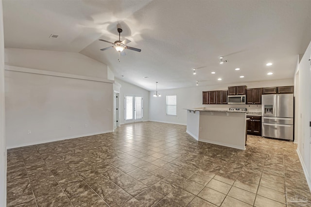 kitchen with stainless steel appliances, vaulted ceiling, a kitchen island with sink, dark brown cabinets, and ceiling fan with notable chandelier