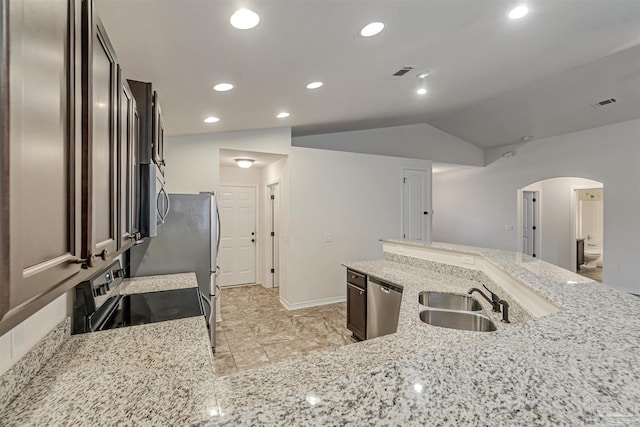 kitchen featuring light stone countertops, sink, appliances with stainless steel finishes, and vaulted ceiling