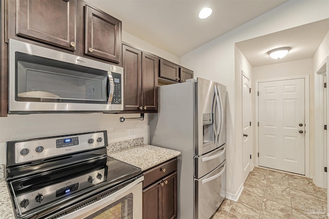 kitchen featuring dark brown cabinetry, stainless steel appliances, light stone counters, and lofted ceiling