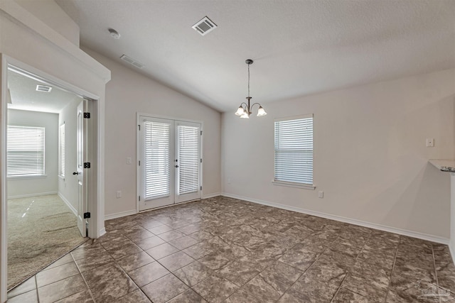 spare room featuring french doors, a textured ceiling, dark tile patterned flooring, a chandelier, and lofted ceiling