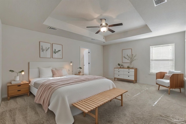 carpeted bedroom with ceiling fan and a tray ceiling