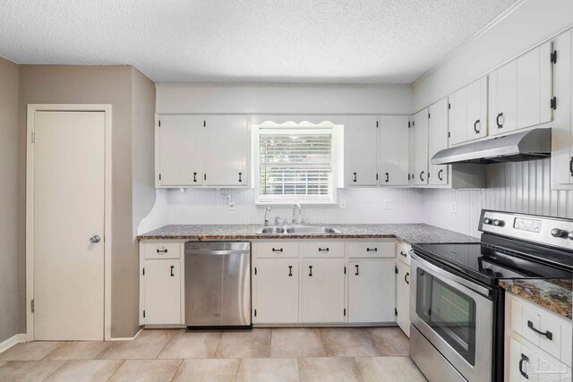 kitchen with white cabinets, stainless steel appliances, sink, light tile patterned floors, and a textured ceiling