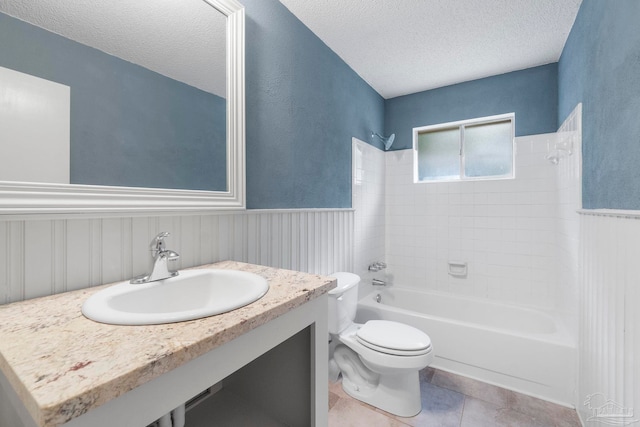 full bathroom featuring vanity, tiled shower / bath combo, toilet, and a textured ceiling