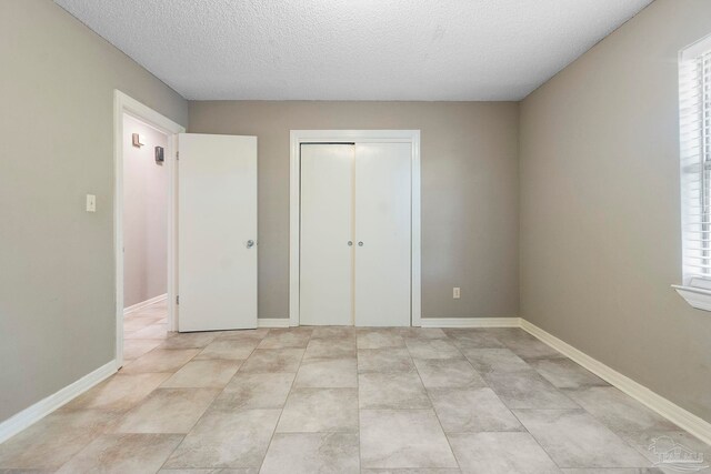 unfurnished bedroom with light tile patterned flooring, a closet, and a textured ceiling