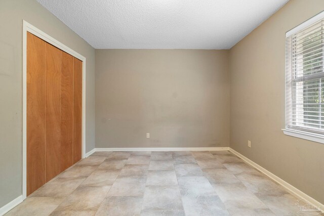 unfurnished bedroom with light tile patterned flooring, a closet, and a textured ceiling