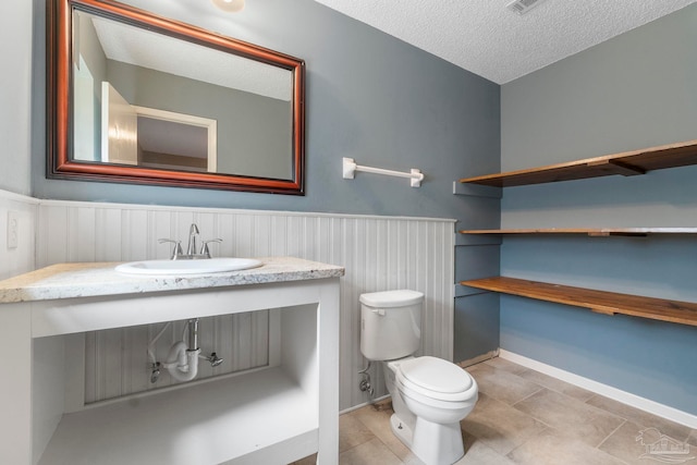 bathroom featuring vanity, a textured ceiling, and toilet